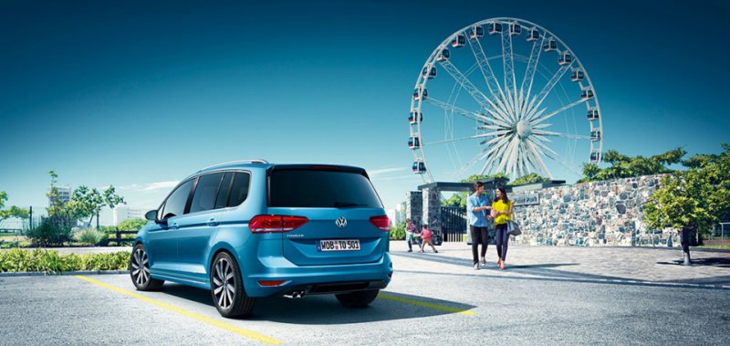 Volkswagen Touran zadní pohled na vůz v modré barvě před zábavním parkem