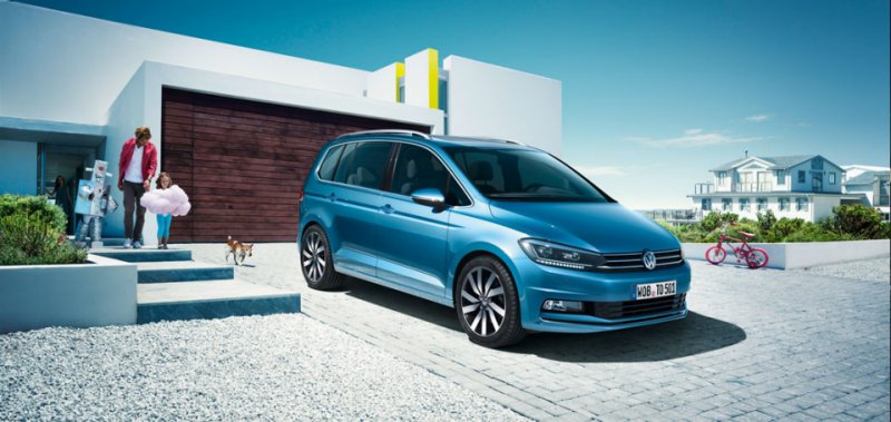 Volkswagen Touran přední pohled na vůz v modré barvě stojící u domu